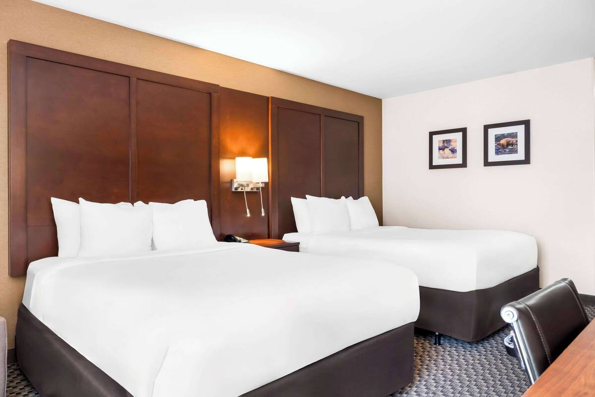 Een hotelkamer met twee bedden, een bureau en een lamp.