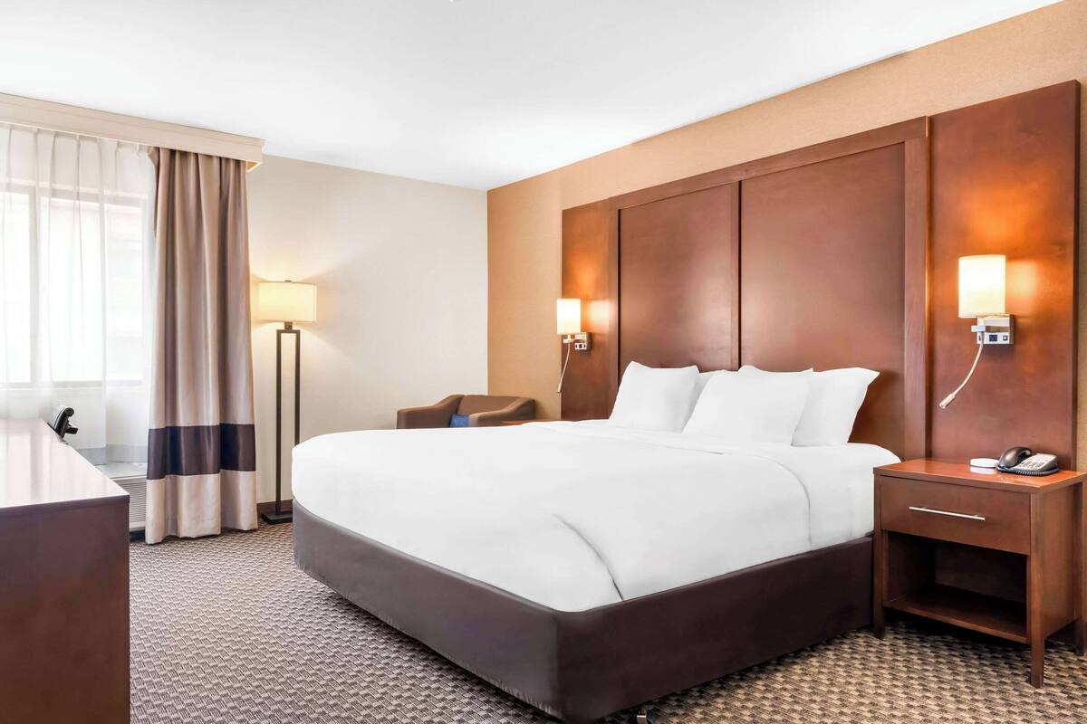 Een hotelkamer met een groot bed, nachtkastjes, een bureau en een lamp.