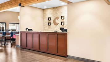 A reception area with a wooden ceiling, a stone wall with a crescent moon design, and a counter with two computers.