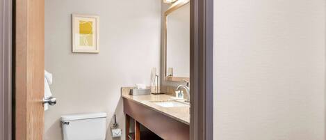 A bathroom with a toilet, sink, and mirror.