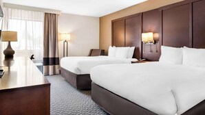 Une chambre d’hôtel avec deux lits, un bureau et une lampe.