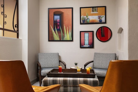 A room with two grey upholstered sofas, a wooden coffee table with three drinks, and a small potted plant.