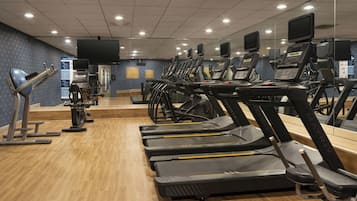A gym with multiple treadmills, exercise bikes, and a mirrored wall.