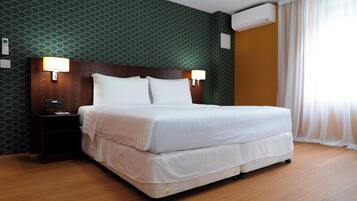 Una camera d'albergo con un letto, due lampade da comodino, un tavolino di appoggio e carta da parati decorata.