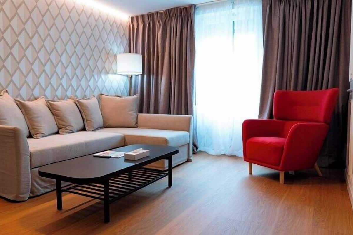 Ein modernes Wohnzimmer mit einem beigen Sofa, einem schwarzen Couchtisch und einem roten Sessel.