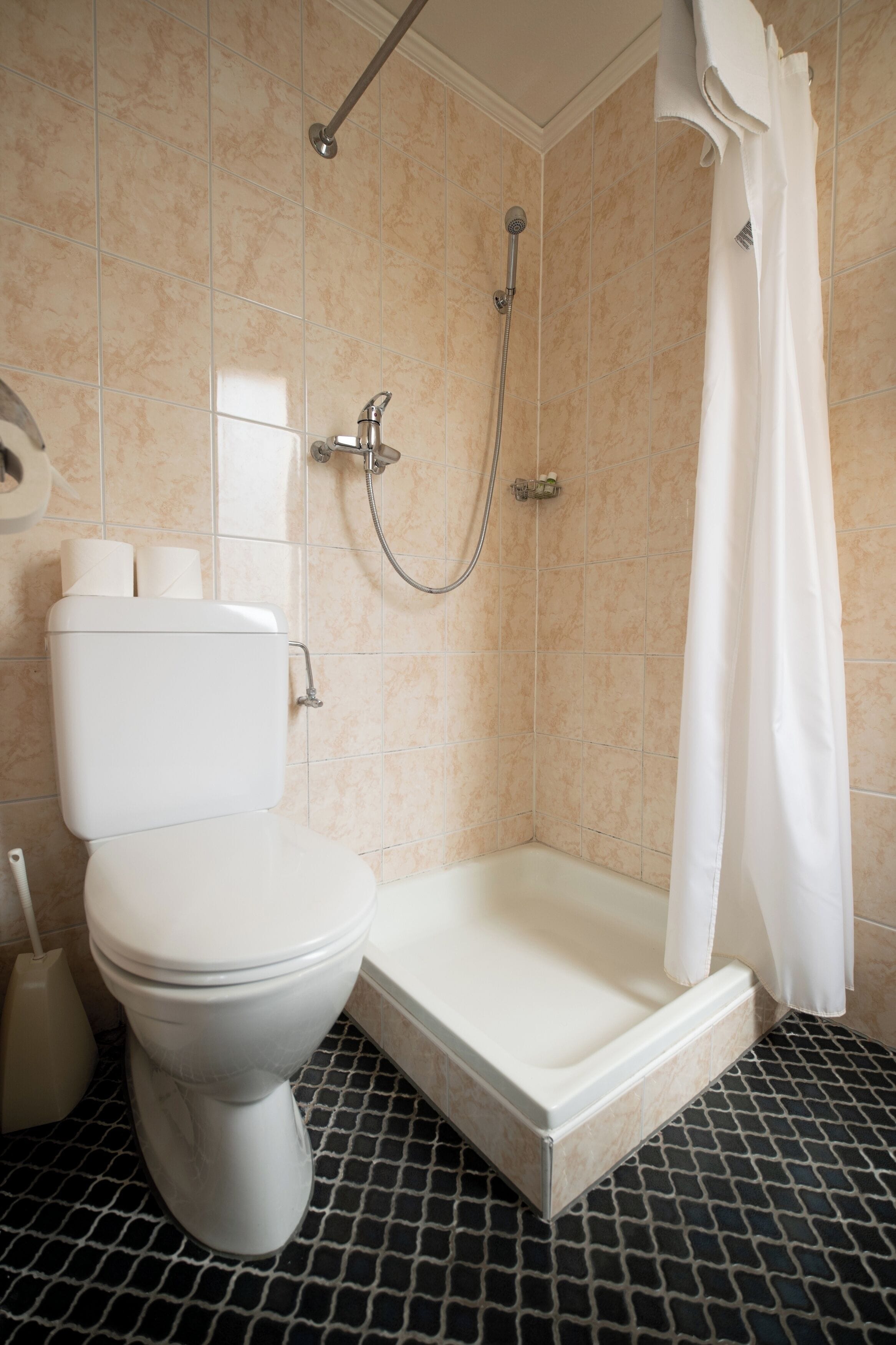 Ein Badezimmer mit Toilette, Dusche und Fliesenboden.