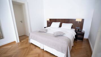 Ein ordentlich bezogenes Bett mit Holz-Kopfteil, zwei Nachttischlampen und einem Nachttisch mit Radio.