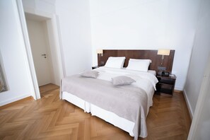 A neatly made bed with a wooden headboard, two bedside lamps, and a nightstand with a radio.