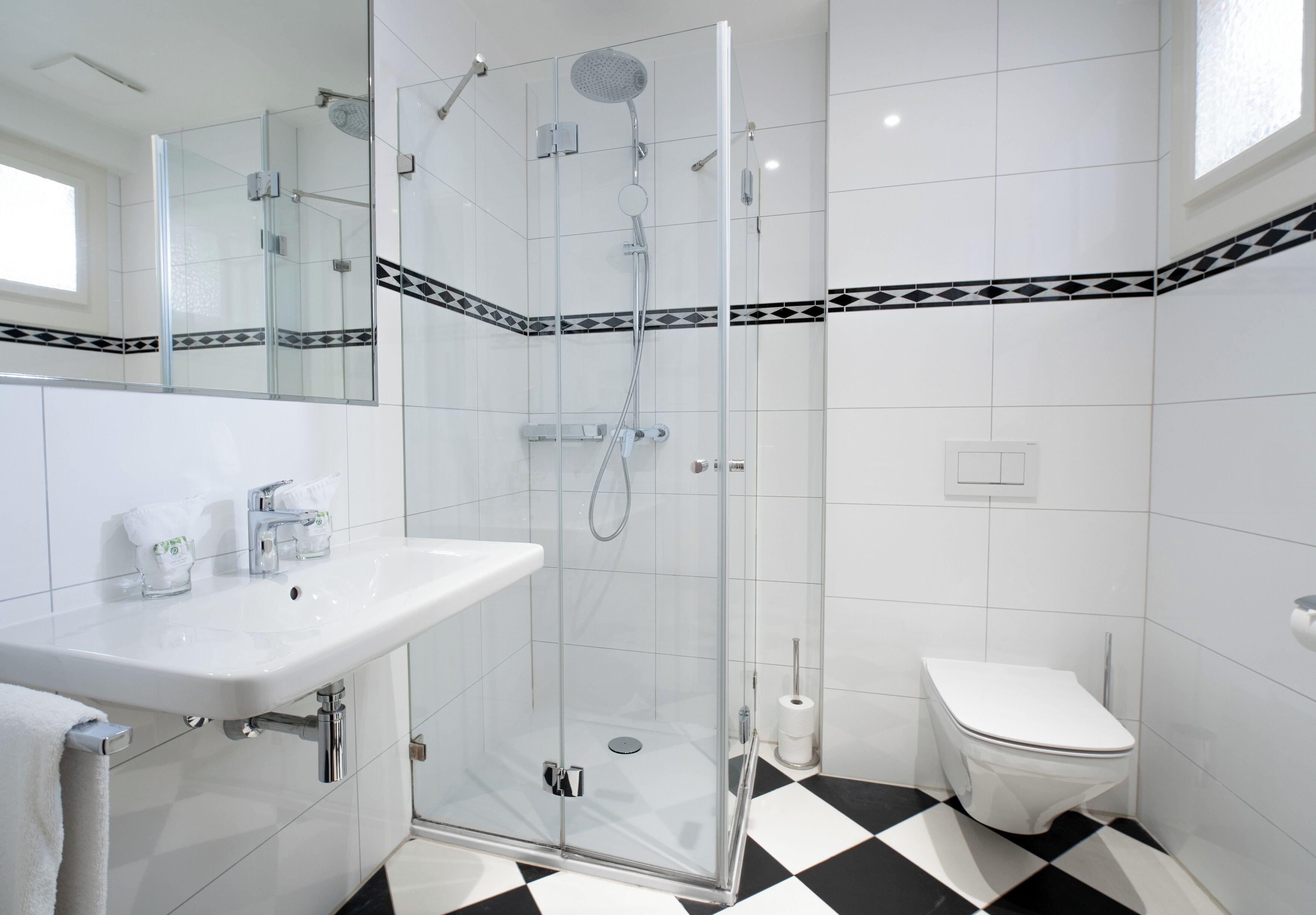 Un baño moderno con ducha de vidrio, un lavamanos blanco y un inodoro.
