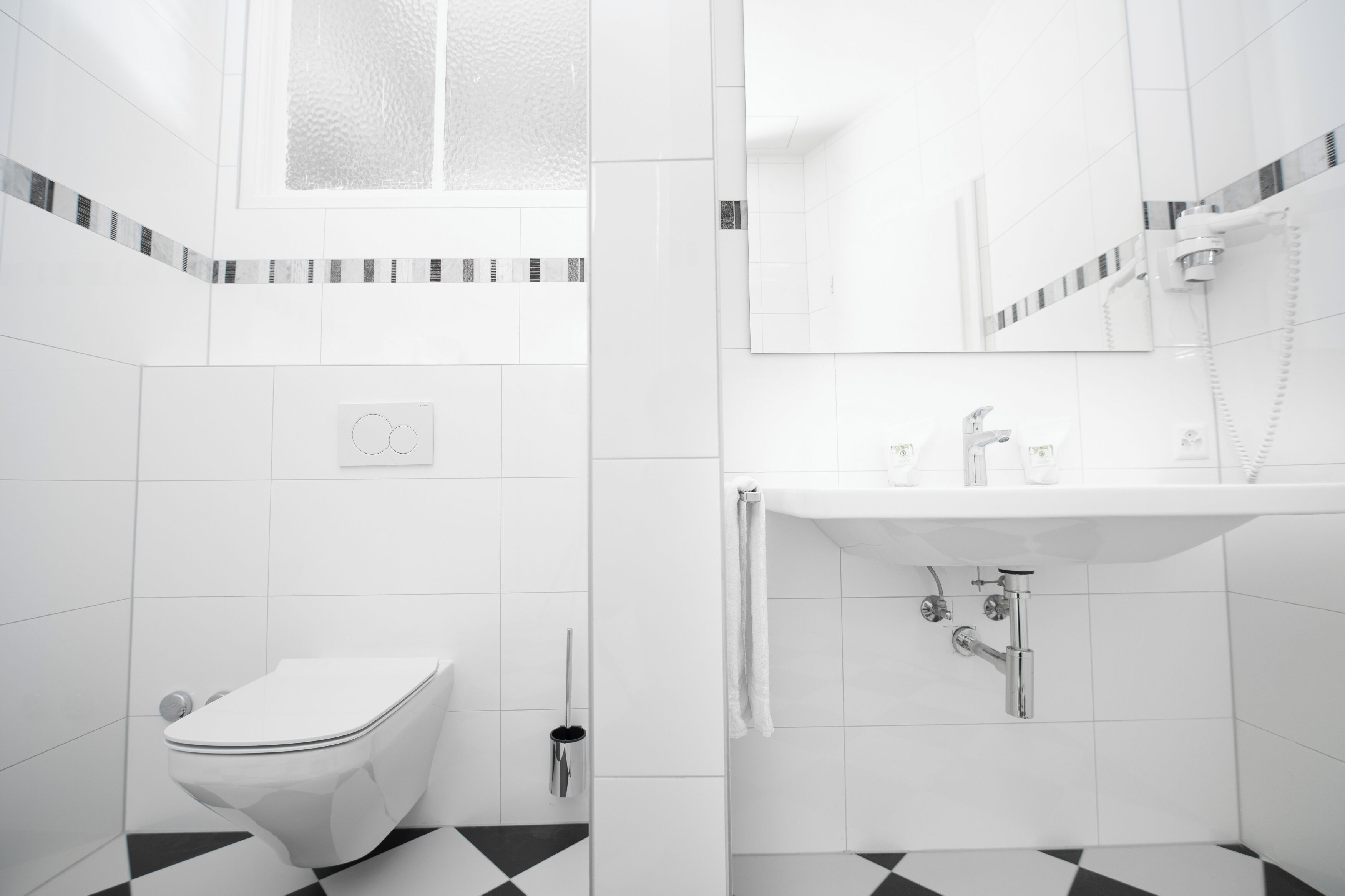 Ein modernes Badezimmer mit Toilette, Waschbecken und Spiegel.