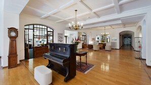 A spacious room with a grand piano, wooden floors, and a chandelier. - J5 Hotels Helvetie Montreux (Montreux)