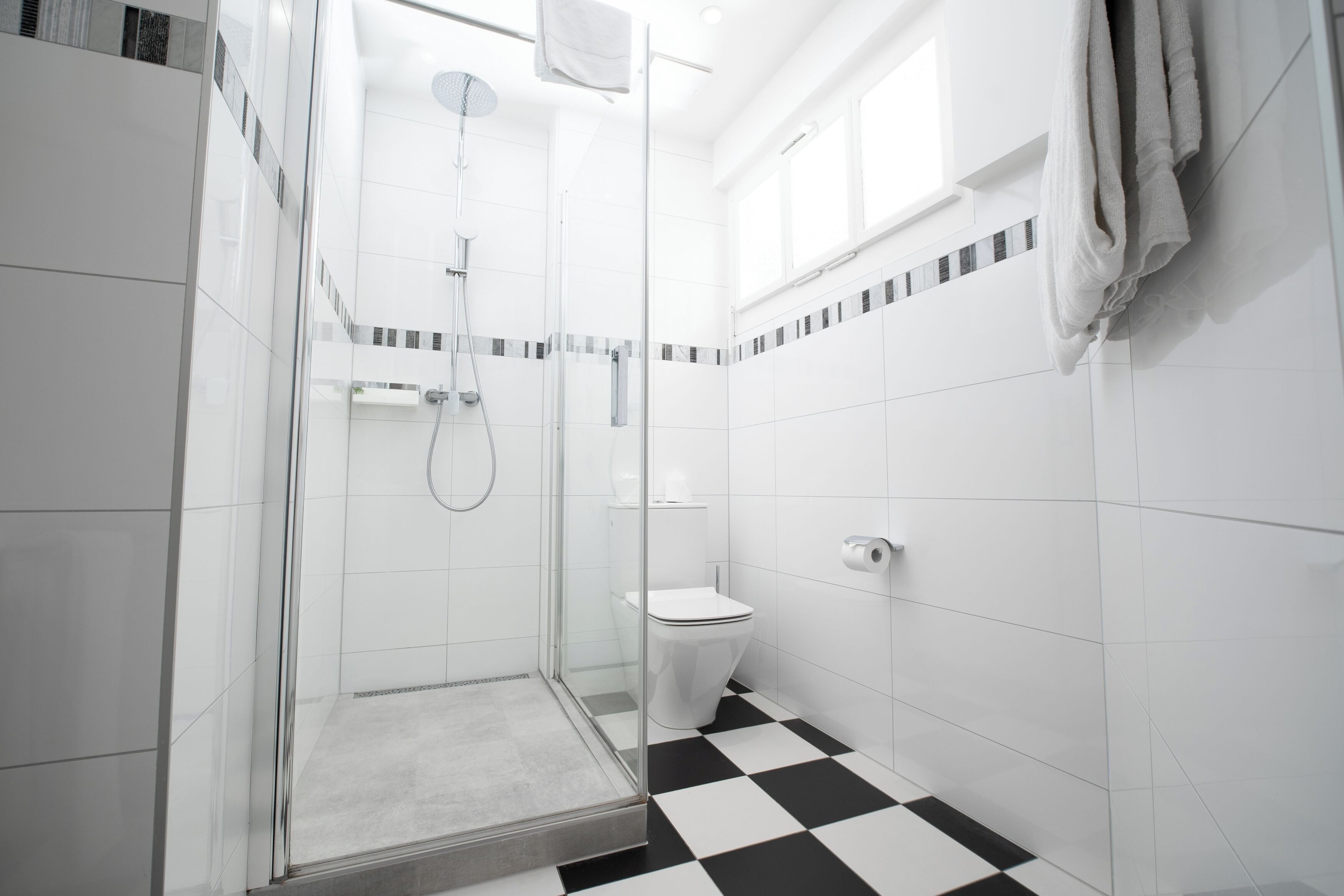 Une salle de bain moderne avec une douche à parois de verre, des toilettes et un carrelage à motifs à carreaux.