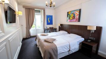 Una camera d'albergo con un letto grande, comodini, una televisione e un quadro appeso al muro.