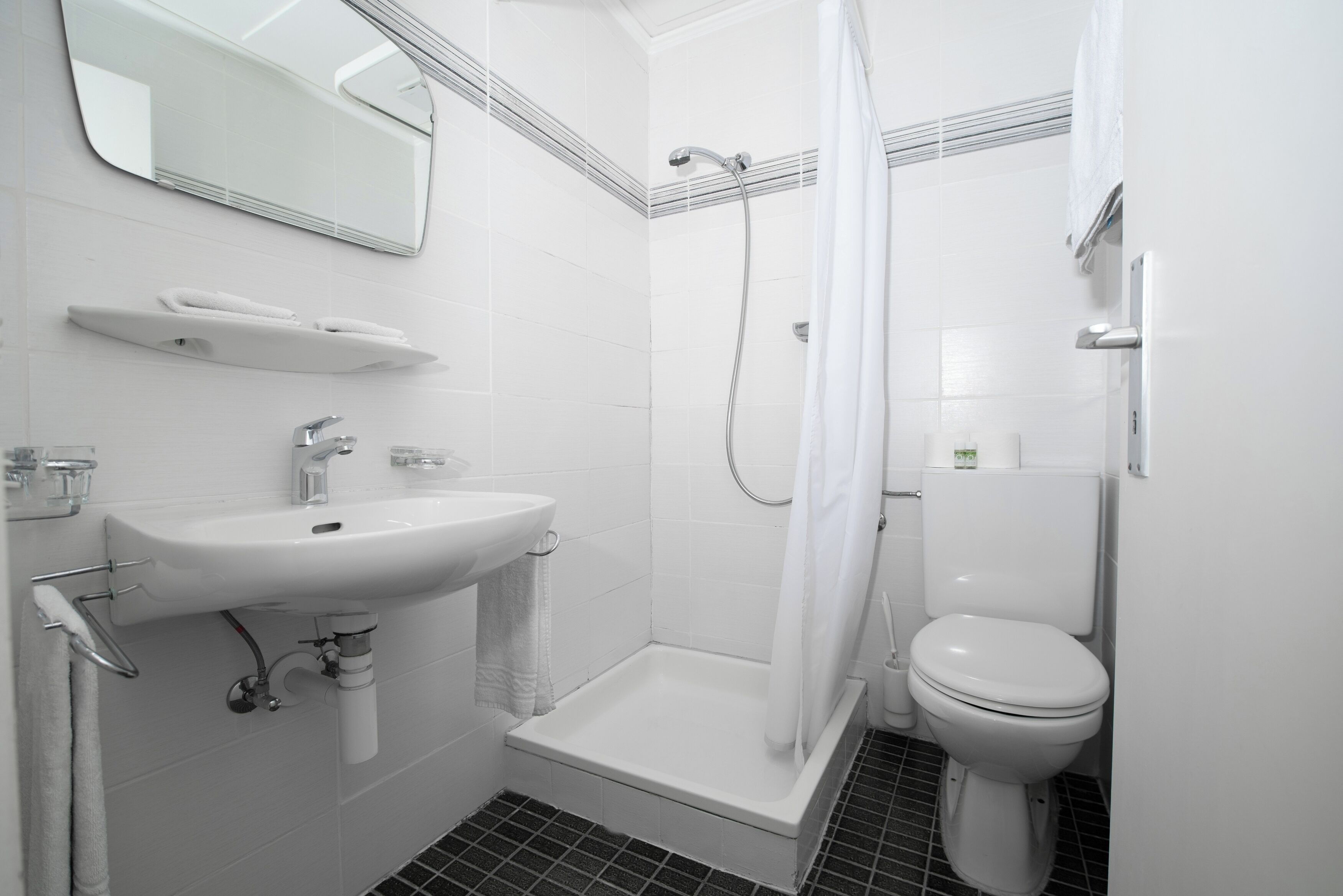 A modern bathroom with a white sink, toilet, and shower.