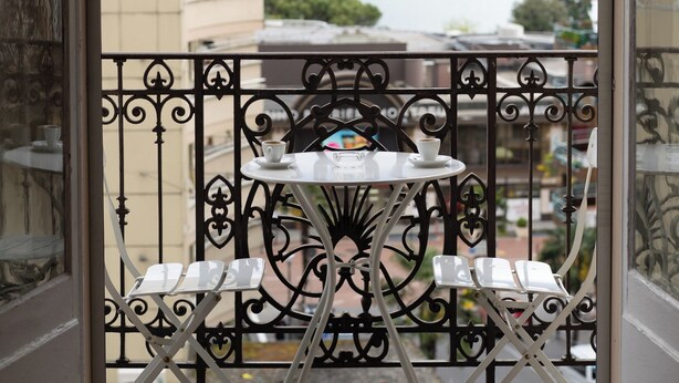 A balcony with a table and chairs, overlooking a lake and mountains. - J5 Hotels Helvetie Montreux (Montreux)