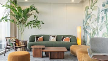 A modern living room with a green sofa, wooden coffee table, and a large potted plant.