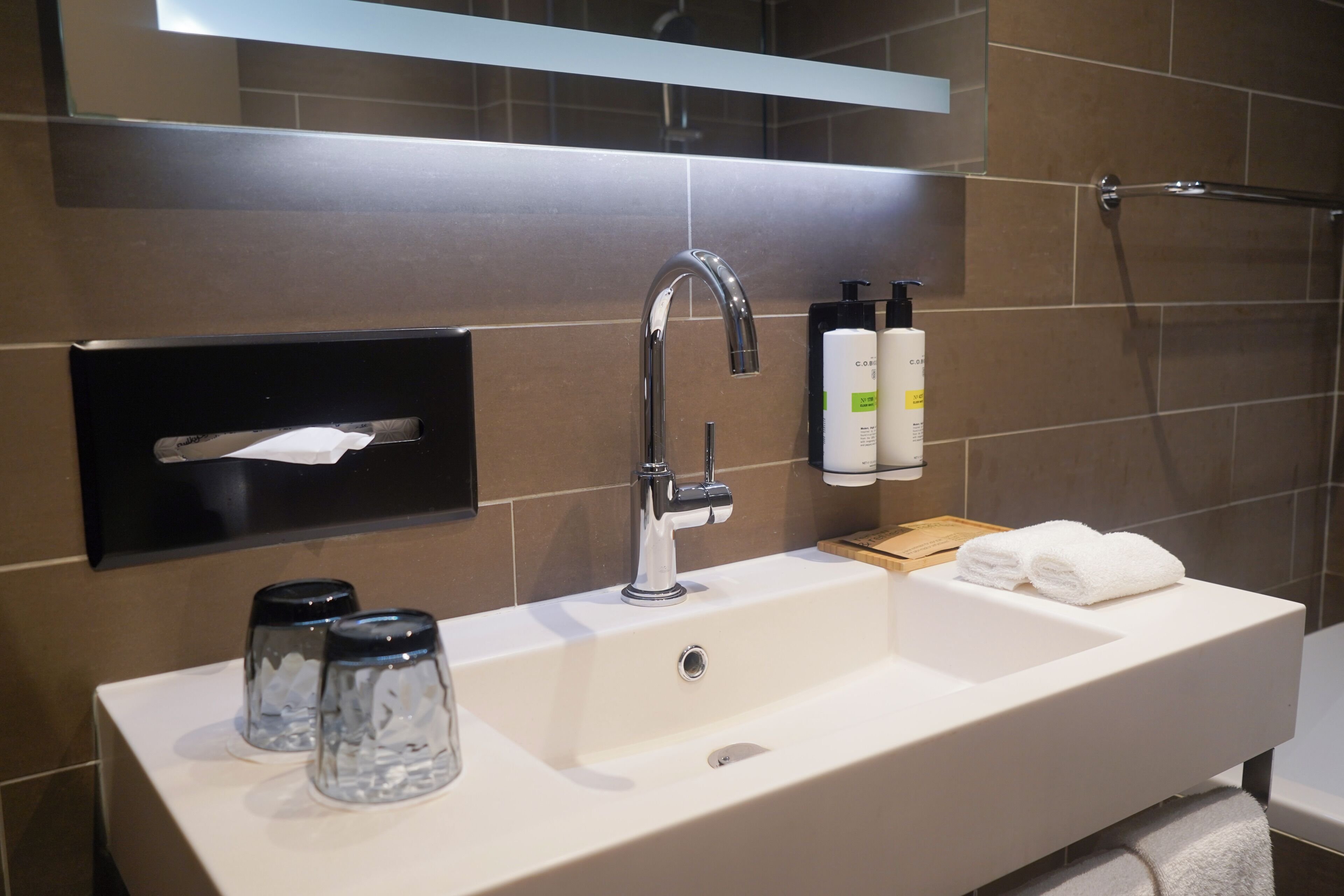 A modern bathroom with a white sink, chrome faucet, and a towel rack.