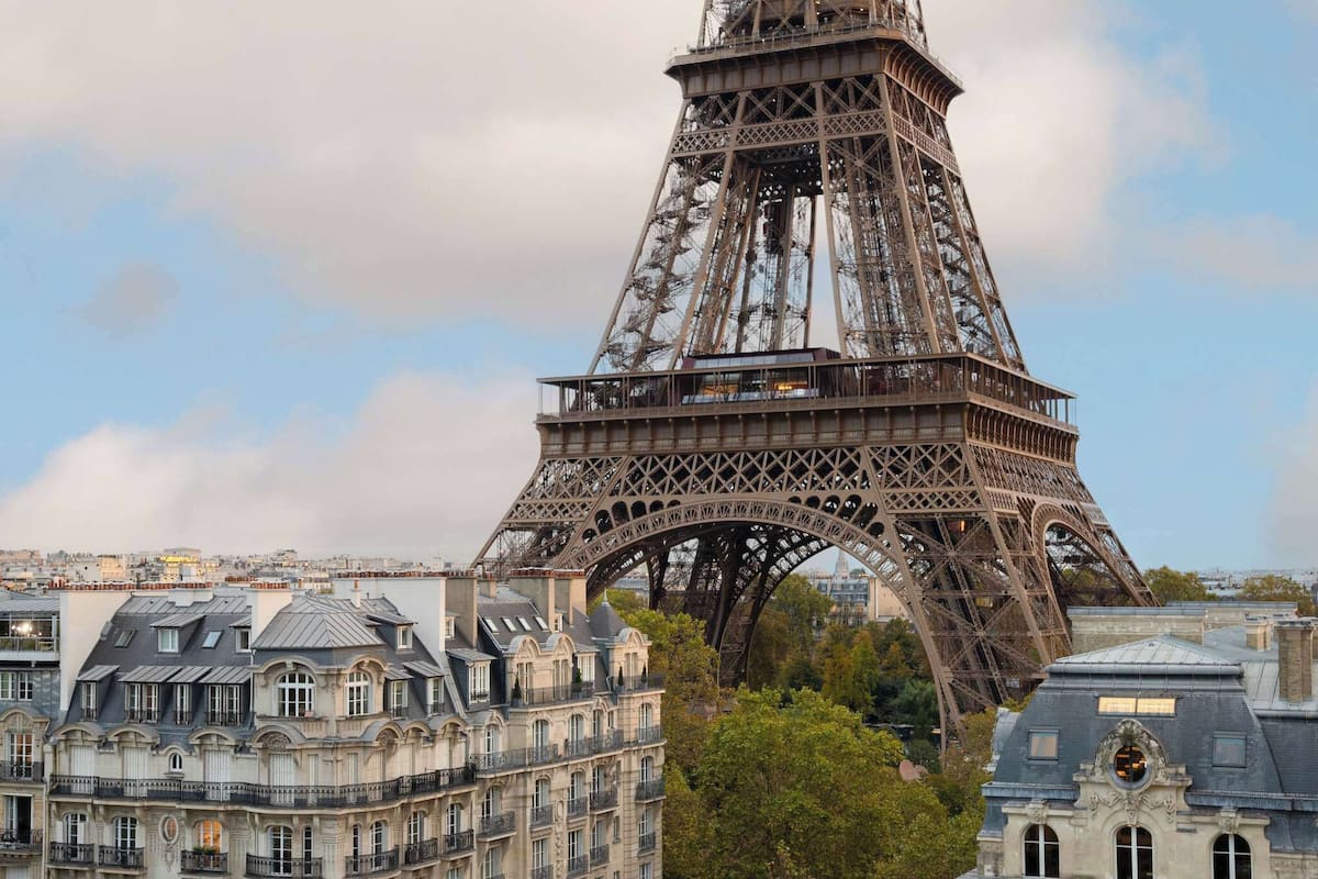 The Eiffel Tower with a view of Parisian architecture and buildings in the foreground.