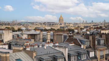 Une vue urbaine avec, au loin, un bâtiment imposant surmonté d’un dôme doré, entouré d’immeubles d’habitation densément regroupés, caractérisés par des toits et des styles architecturaux variés.