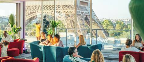 Un interior moderno con zonas de estar y amplios ventanales que ofrecen vistas a la Torre Eiffel.