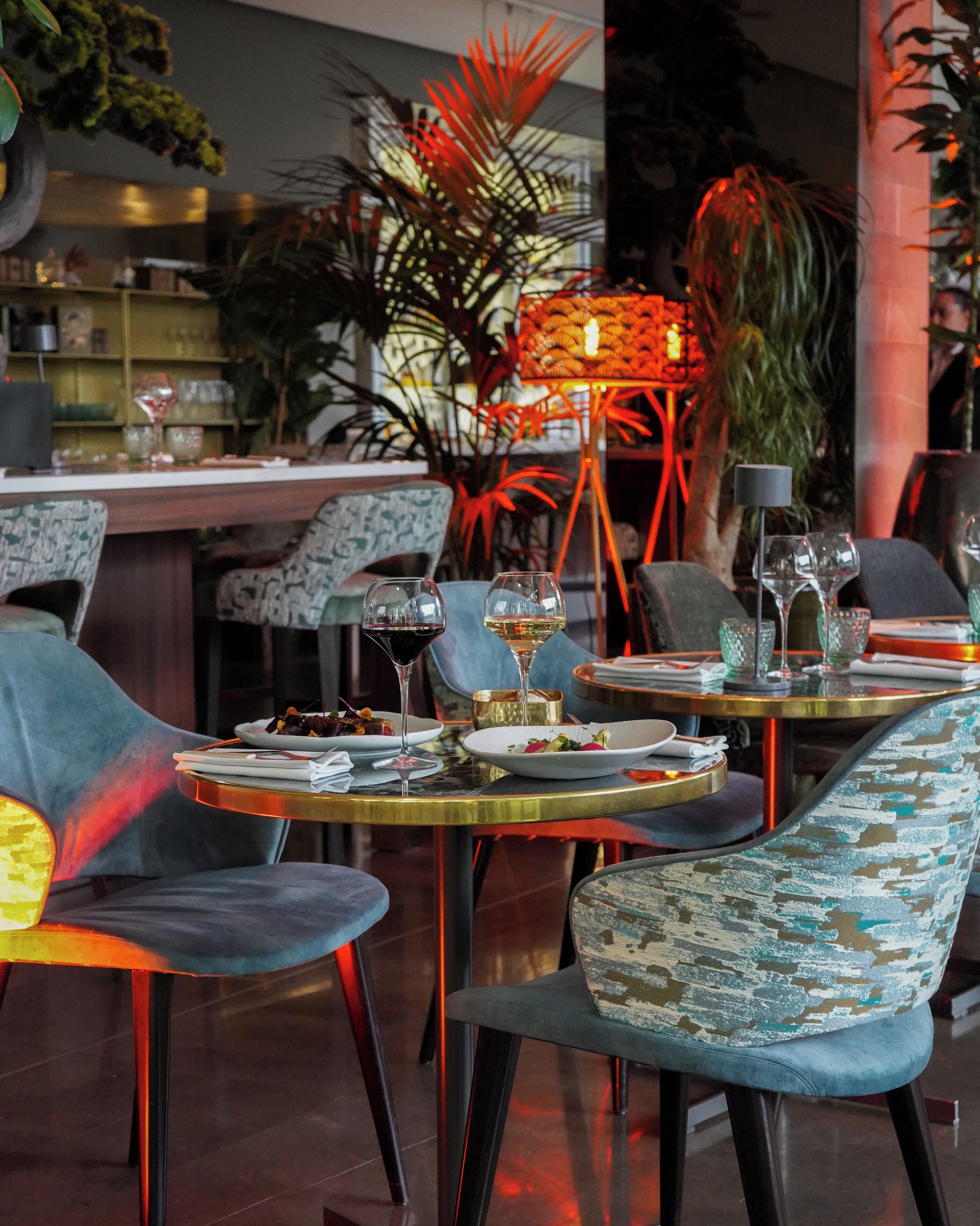 A restaurant interior with round tables, chairs, and a bar area.