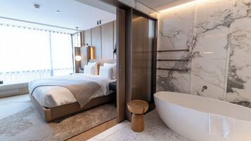Une chambre moderne avec un grand lit, un tabouret en bois et une baignoire sur pieds.