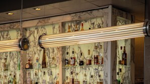 A bar with a marble countertop, hanging lights, and a variety of liquor bottles.
