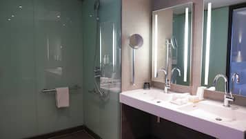 Un bagno moderno con doccia vetrata, due lavabi e ampi specchi.