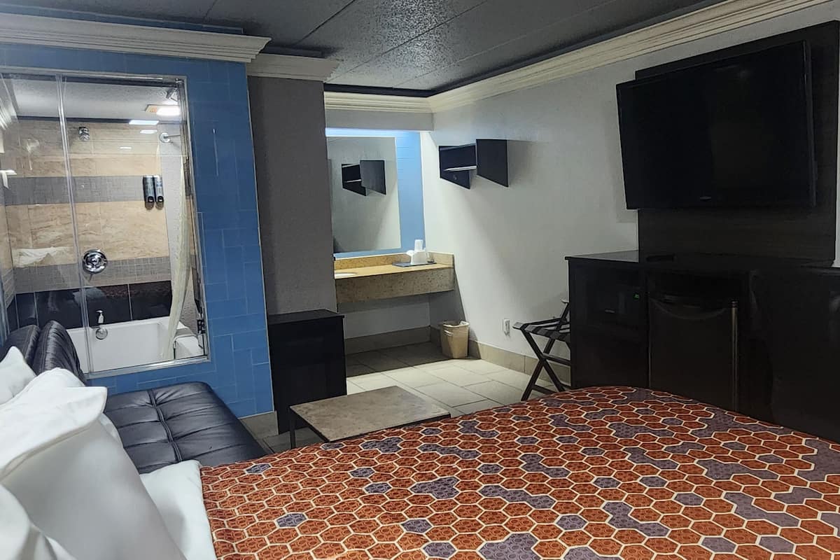 A hotel room with a bed, a bathroom, a TV, and a desk.