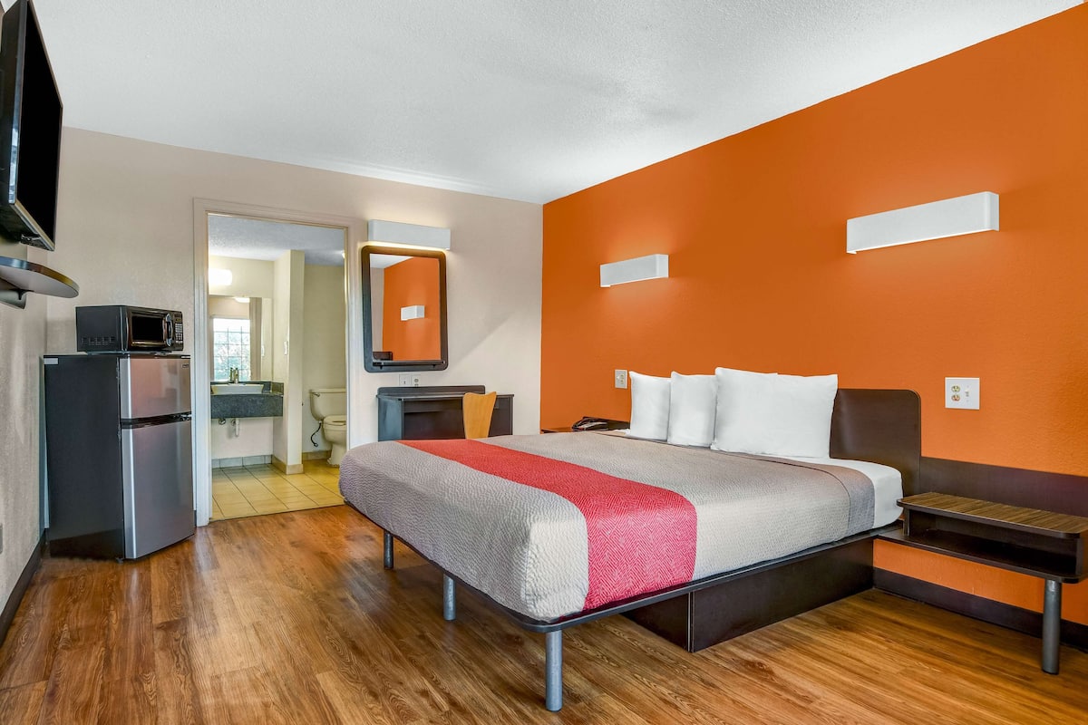 Una habitación de hotel con cama, escritorio, microondas y refrigerador.