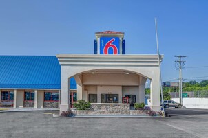 Un motel con un llamativo letrero con el número '6', techo azul y fachada de piedra.