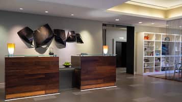 A reception area with two wooden reception desks, a glass-top counter, and a wall-mounted sculpture.