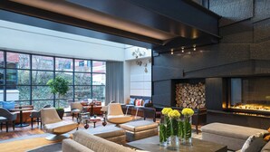 Un salon moderne doté d’une cheminée, de sièges confortables et de grandes fenêtres offrant une vue sur l’extérieur.