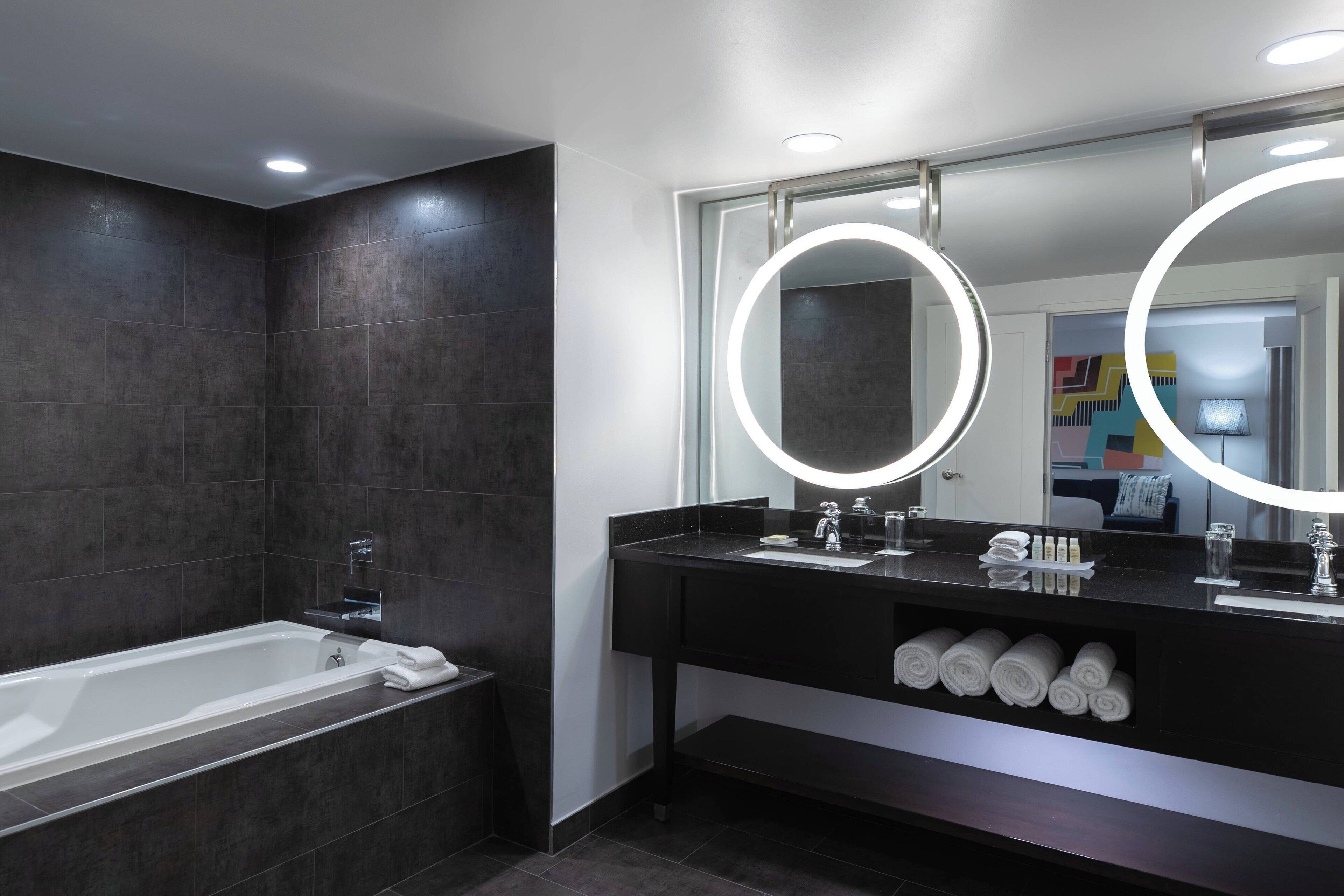 Un baño moderno con bañera, tocador con espejo y barra para toallas.