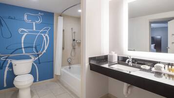 A modern bathroom with a toilet, bathtub, and a sink with a mirror.