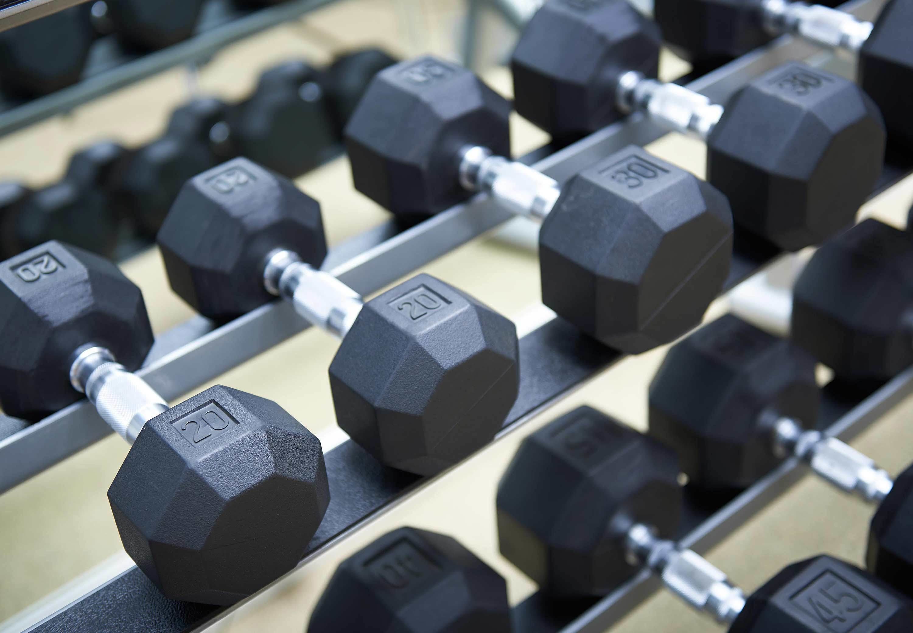 A rack of hexagonal dumbbells with visible weight markings.