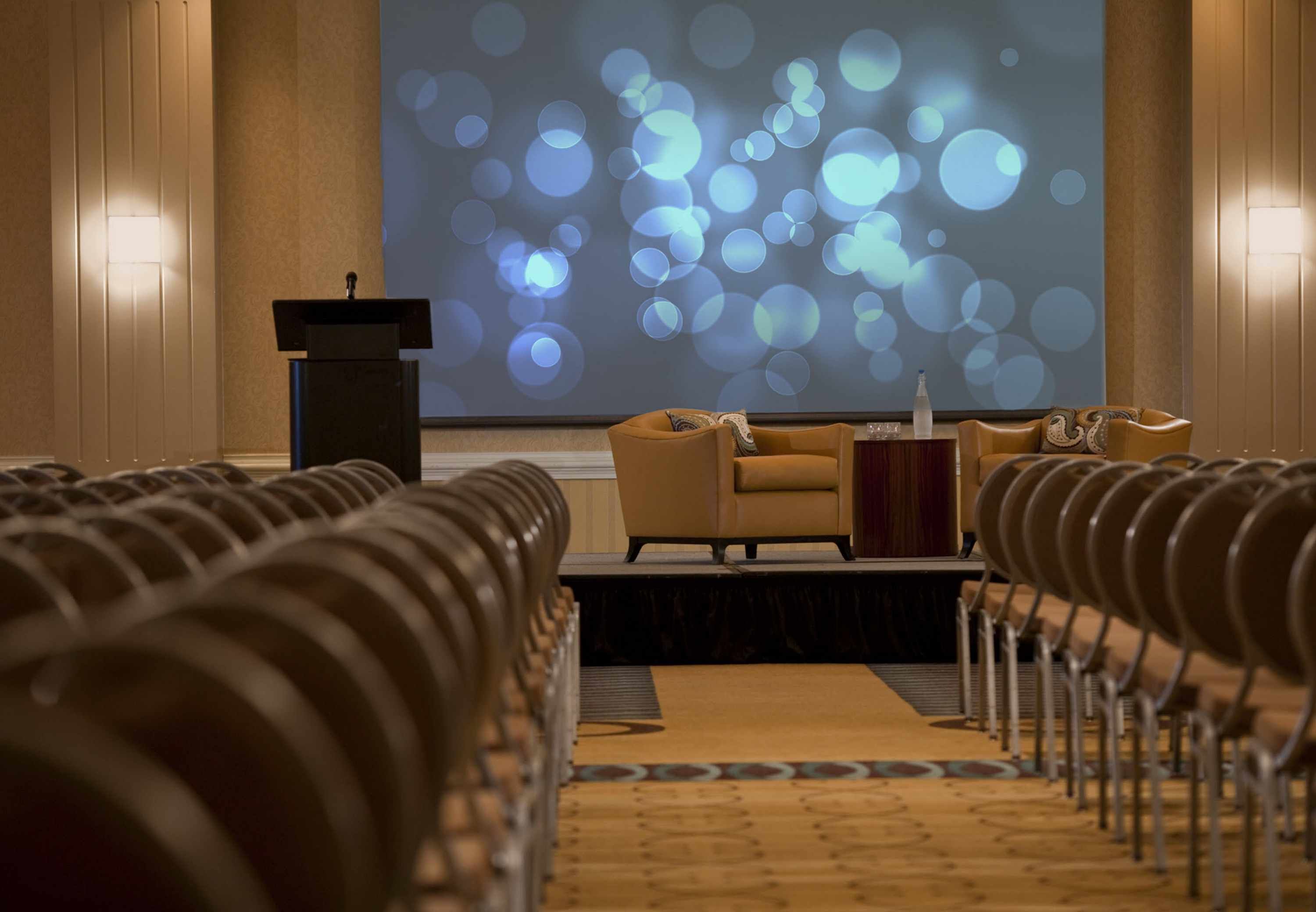 A conference room with a podium, a sofa, and rows of chairs.