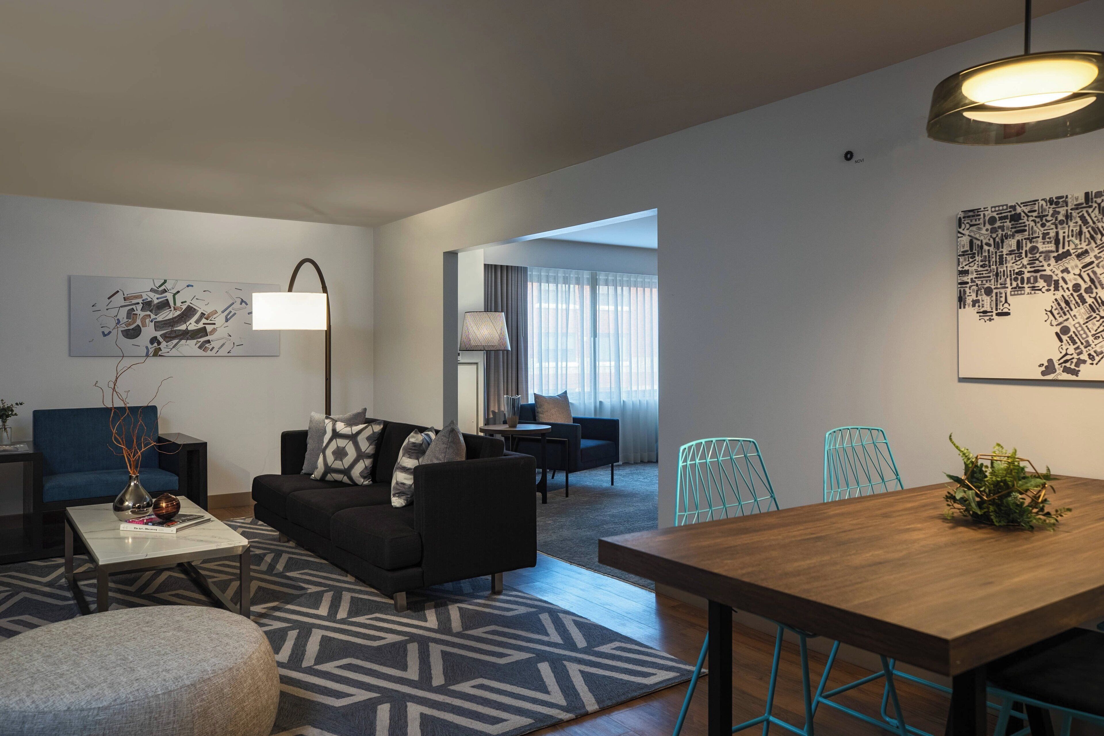 A modern living room with a sofa, coffee table, and a dining area with a wooden table and chairs.