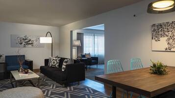 A modern living room with a sofa, coffee table, and a dining area with a wooden table and chairs.