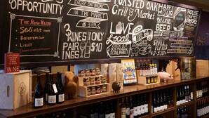Un tableau noir servant de menu, avec une sélection de vins à déguster, un panneau représentant Détroit, et divers plats et boissons proposés.