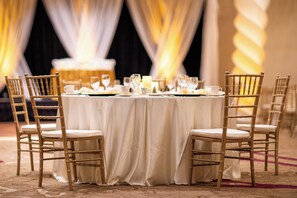 Formal dining area with a round table, six cushioned chairs, and elegant table setting.