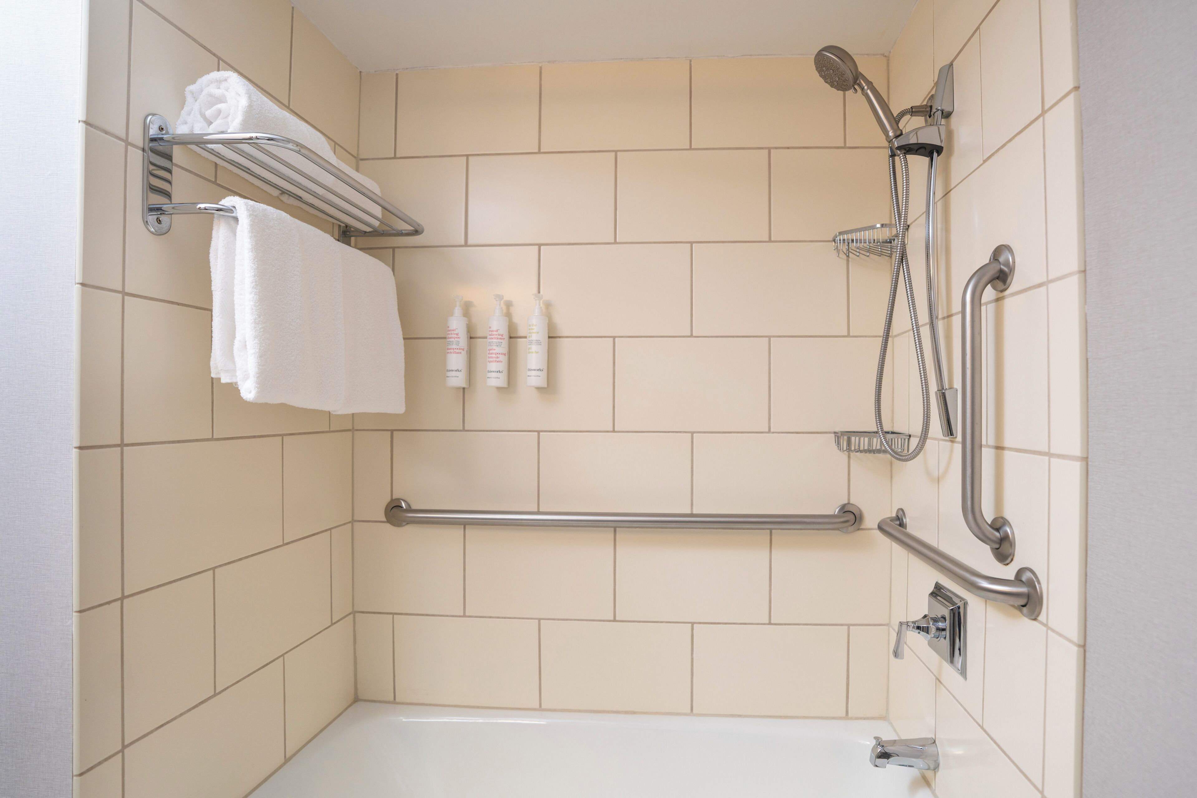 Un baño con bañera, ducha, toallero y barras de apoyo.