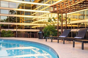 A modern building with a pool area, including lounge chairs and a pergola. - Walnut Creek Marriott (Walnut Creek)