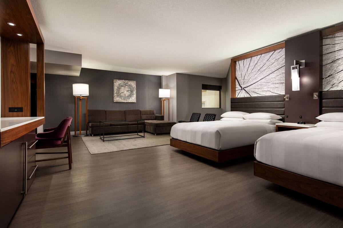 Ein modernes Hotelzimmer mit einem großen Bett, einem Schreibtisch, einem Sessel und einer Couch.