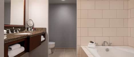 A modern bathroom with a large bathtub, a vanity with a mirror, and a toilet.