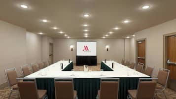A conference room with a long table, chairs, and a screen displaying the Marriott logo.