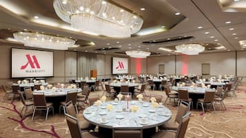 A conference room with round tables, chairs, and chandeliers.