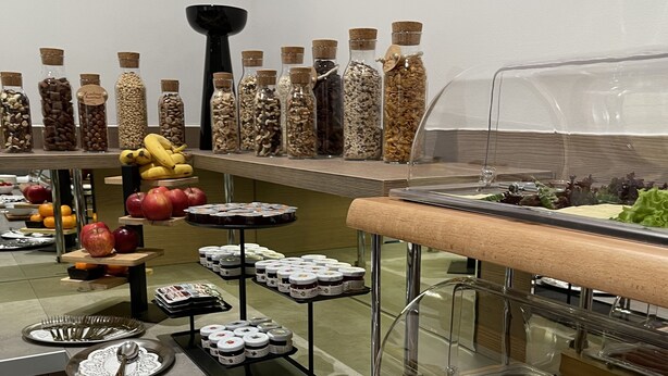 Un bufé con diferentes opciones de comida, incluyendo frutas, frutos secos y embutidos.