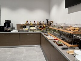 Una cocina moderna con cafetera, mesa de buffet con diversas opciones de comida y un lavamanos.