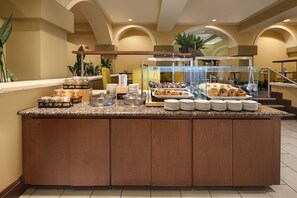A buffet counter with various food items, including pastries and condiments, in a hotel setting. - Embassy Suites by Hilton Dallas Park Central Area (Dallas)